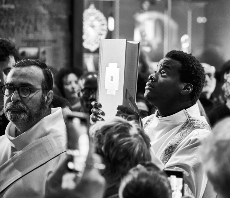 Jeune prêtre noir tenant la bible devant son visage