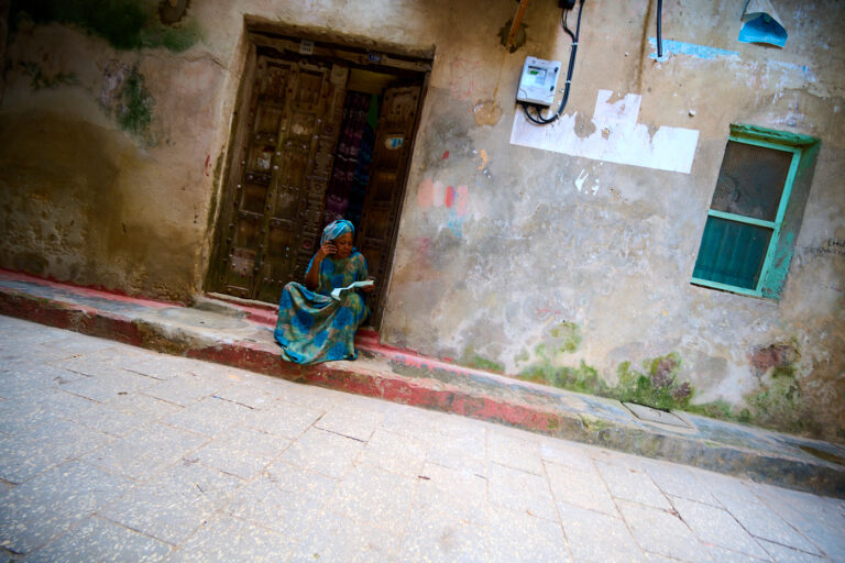 Femme devant une porte sculptée à Stonetown (Zanzibar)