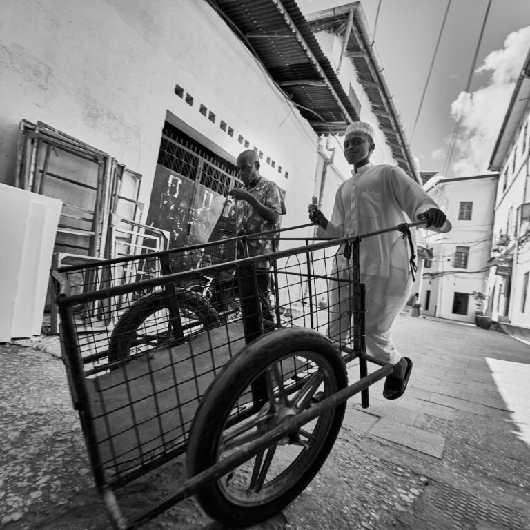 Jeune homme en blanc à la charrette dans une rue de Stonetown à Zanzibar