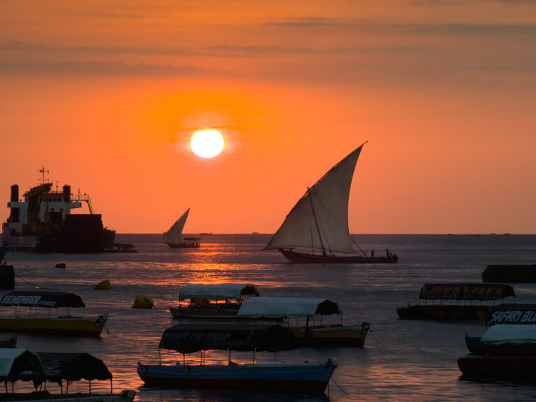 Boutre (dhow) sous voile au coucher de soleil, baie de Stonetown à Zanzibar